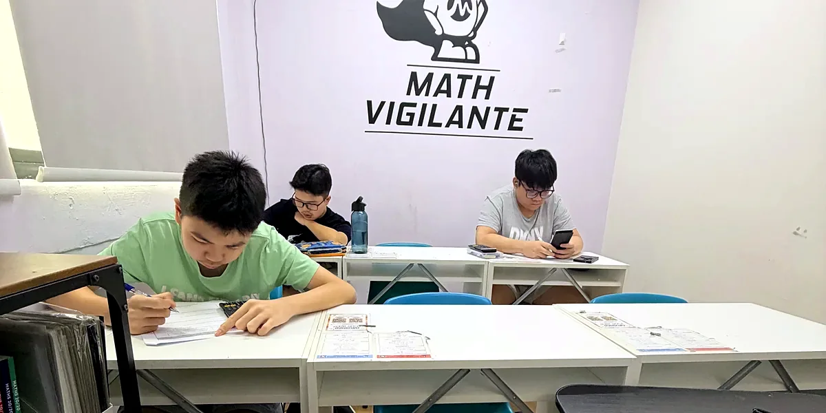 Two Math Vigilante students working at their desks under the Math Vigilante logo